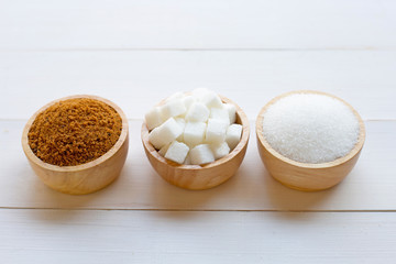 Various types of sugar on wooden background.