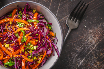 Coleslaw in a gray bowl on dark background. Red cabbage and carrot salad.