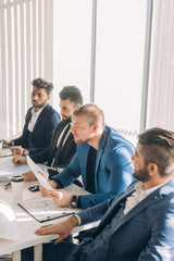 Obraz premium Diverse business executives discussing project sitting at conference table, multiracial partners talking about marketing plan at corporate briefing, african manager offering new idea at group meeting