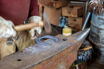 Schmiedearbeit, ein Hufeisen wird auf einem Amboss bearbeitet (geschlagen)