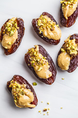 Dates stuffed with peanut butter and pistachios on white background.