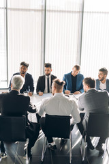 Obraz premium Business Discussion Meeting Presentation Briefing with the participation of male stuff only. Formally dressed multiracial men, working as a team, working out new strategy of development