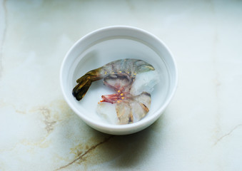 Raw tiger prawns in a bowl of water
