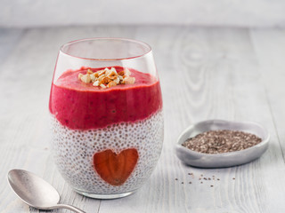 Idea for healthy breakfast on Valentine's Day: Chia pudding with red berry puree, chopped almonds on top and strawberry in the shape of heart. Copy space for text