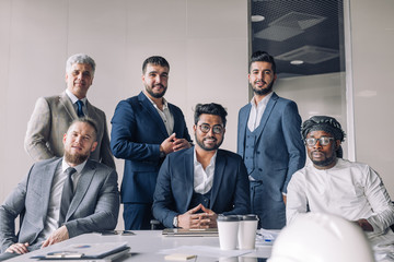Formal meeting of several multi-ethnic male colleagues gathered in executive s office to discuss new ideas