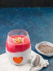 Fototapeta na wymiar Idea for healthy breakfast on Valentine's Day: Chia pudding with red berry puree, chopped almonds on top and strawberry in the shape of heart. Copy space for text