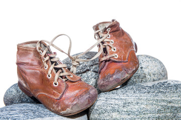 old, worn children's shoes are standing on round stones