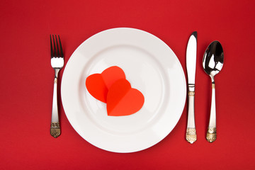 Festive table setting for Valentine's Day with fork, knife,  hearts on a red background. Top view. - Image.