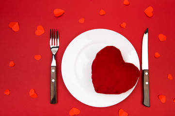 Heart on a plate for dinner. A romantic evening with hearts on red background.