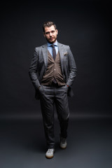 Obraz premium Full length portrait of a fashion male model over black background. Looking at camera.