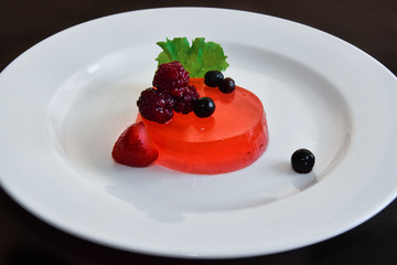 Fruit jelly with berries on a white plate.