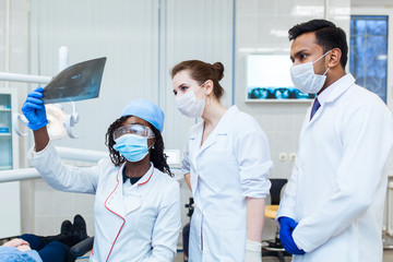 A multinational group of dentists examines x-rays in the presence of a patient. Practice at a medical university.
