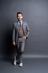 Full length portrait of a fashion male model over grey background. Looking at camera.
