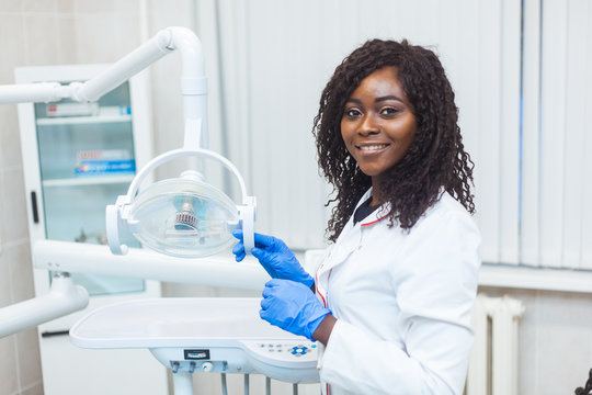 Portrait of female black dentist in dental office. She standing at her office and she has beautiful smile.