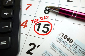 Form 1040, calculator and pen on calendar showing tax day date - April 15,   2019