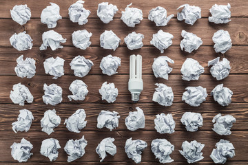 Ideological concept with wastepaper light bulb on wooden table