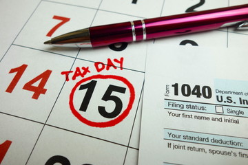 Tax day marked on April 2019 calendar with 1040 form and pen