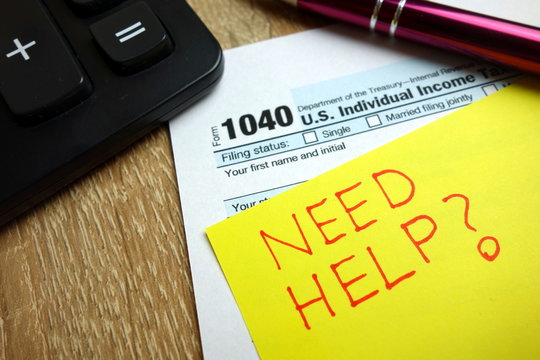 Need help text with 1040 tax form, calculator and pen on desk