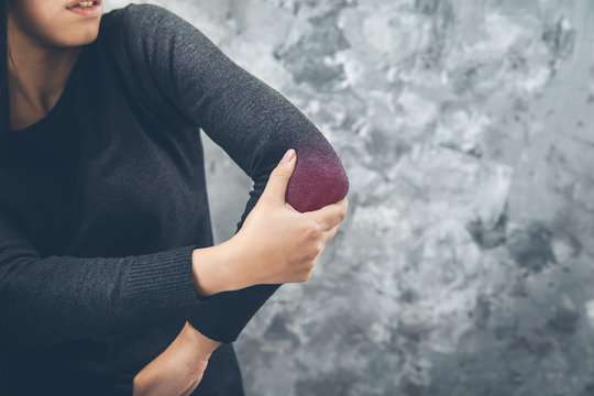 woman pain elbow on dark background