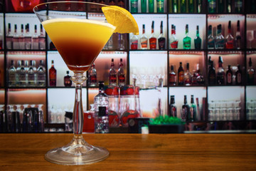 Tequila sunset cocktail in martini glass decorated slice of orange