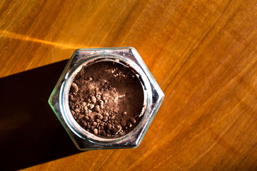 Cocoa powder in glass jar lying on wooden brown table, flat lay view, healthy diet