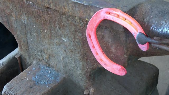 Schmiedearbeit, ein hei&szlig;es Hufeisen wird auf einem Amboss bearbeitet (geschlagen)
