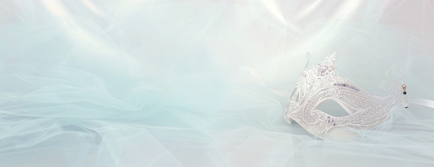 Banner of elegant and delicate white lace venetian mask over mint chiffon background.