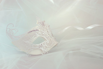 Photo of elegant and delicate white lace venetian mask over mint chiffon background.