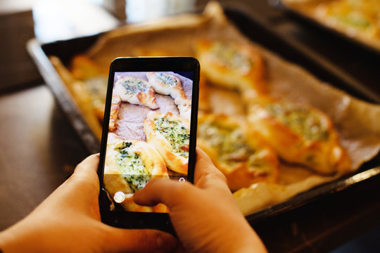 Female hands hold phone and take picture of a georgia adjarian Khachapuri with spinach and cheese 