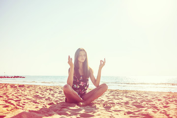 Fototapeta na wymiar Girl meditates in the lotus position on the beach