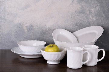 White dishware stacked on a wooden table against grey background on wooden table