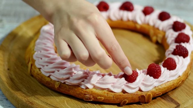 Woman in the kitchen making Paris Brest with raspberry.