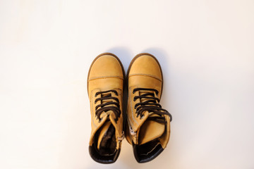 top view of a pair of yellow leather child shoes on a white background