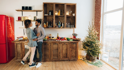 Obraz na płótnie Canvas African-american couple spending Christmas morning at kitchen
