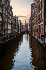 Fototapeta na wymiar Amsterdam canal view bordered by bricks residence and housing are during the sunset, Amsterdam, Netherlands