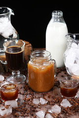 Milk bottles, ice and coffee jar on wooden background. Pieces of ice and coffee beans scattered on the table. The concept of still life. Food photo