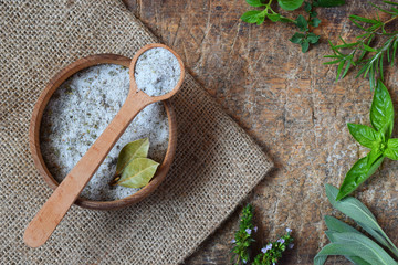 Ayurvedic herbal salt in wooden spoon. Sea salt with aromatic herb - rosemary, oregano, sage, marjoram, basil, thyme, mint, bay leaf. Copy space