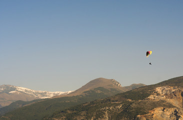 Fototapeta na wymiar paroplan is flying in the sky on the mountains