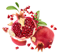 Flying in air fresh ripe whole and cut pomegranate with seeds and leaves