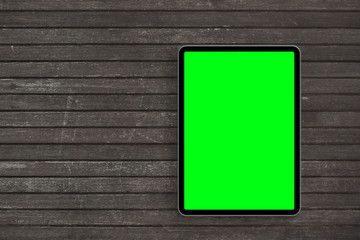 Top view of digital tablet computer with green isolated screen on wooden desk. Concept workplace.