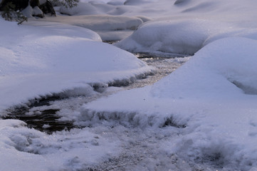 Winter adventures. Creek in the snow. Carpathians. Ukraine.