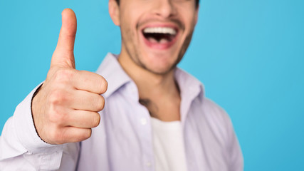 Pleased man showing thumb up and smiling