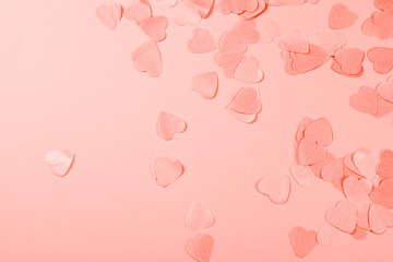 Coral background with heart-shaped confetti.