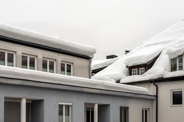 Roof of building with window and thick snow layer in winter. Snowfall and blizzard weather forecast