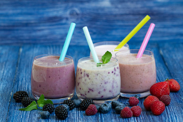 Raspberry, strawberry, blackberries, blueberry smoothie on blue wooden background. milkshake with fresh berries. healthy fruit smoothie with ingredients. well being and weight loos concept