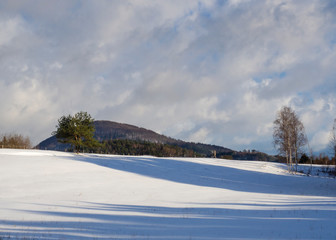 winter field and forest countryside snow covered landscape with trees, hill and wooden high seat in luzicke hory mountain