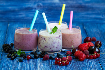 Raspberry, strawberry, blackberries, cherry smoothie on blue wooden background. milkshake with fresh berries. healthy fruit smoothie with ingredients. well being and weight loos concept