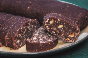Chocolate salami, a traditional dessert with hazelnuts and broken cookies in the plate. closeup
