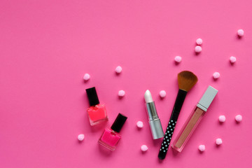 Nail polishes, lipstick on a pink background. Makeup cosmetics for young women or teenager. Copy space. Top view