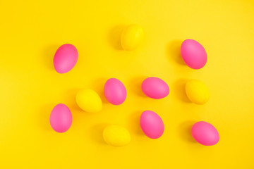 The creative layout of eggs is colored in yellow and pink colors on a yellow background